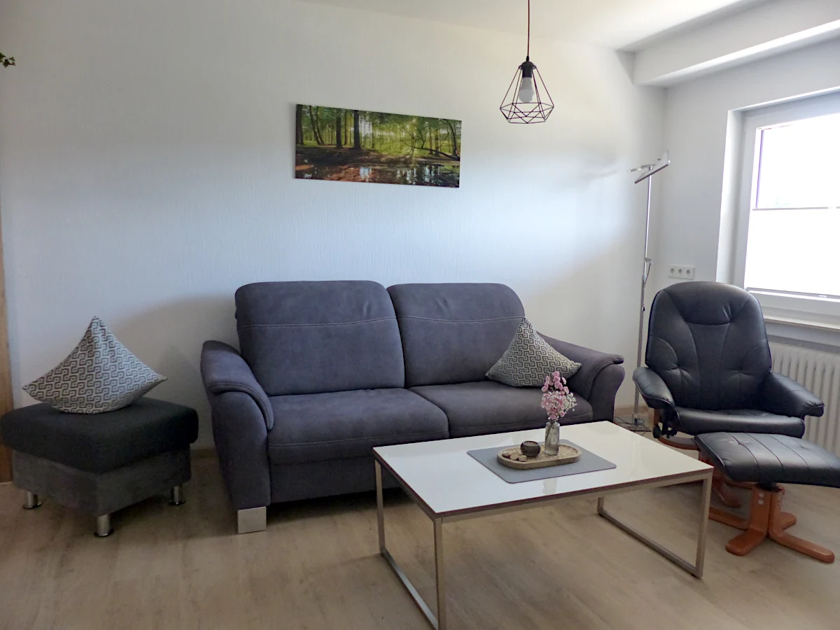 Wohnzimmer mit Sofa, Sessel und Hocker